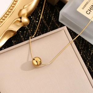 Elegant gold bead pendant necklace with sleek snake chain displayed on jewelry box