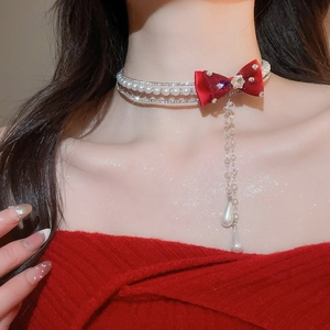 Detail of red silk bow choker with sparkling diamond chains and pearl tassel pendants