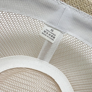 Detail of 100% paper straw hat interior with mesh lining, size 58 label, and sweatband