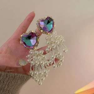 Close-up of heart-shaped rhinestone earrings with elegant white pearl tassels