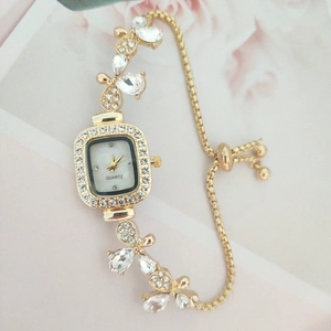 Detailed close-up of golden petal-shaped watch strap with sparkling rhinestones and butterfly
