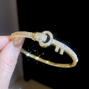 Macro shot of 18k gold plated key-shaped bangle with pavé-set shimmering zircon details