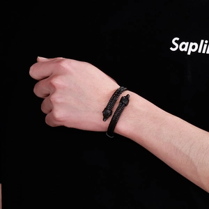 Close-up of black stainless steel twisted cable bracelet with dual wolf head detailing