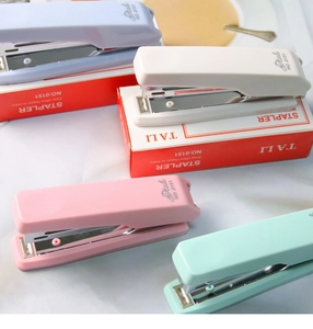 Close-up of pastel staplers in macaron colors with packaging on a white desk