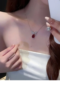 Detailed view of zircon water drop necklace with red gemstone and matching earrings