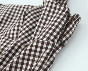 Detailed macro shot of the side hidden zipper on brown and white checkered woven top