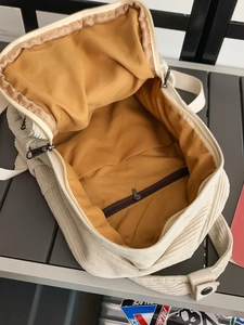 Fashionable beige corduroy backpack for women with open view of yellow lining and pocket