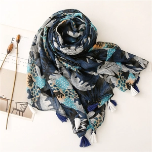 Detail of printed cotton linen scarf featuring blue tropical leaves and fringe tassels