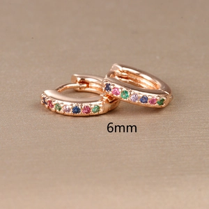 Macro shot of 6mm rose gold huggie hoop earrings with colorful inlaid crystals