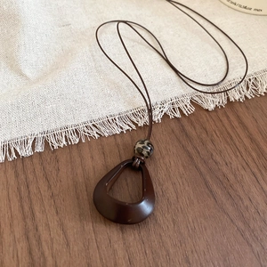 Detail of vintage resin pendant necklace with leopard print bead on rustic wood background