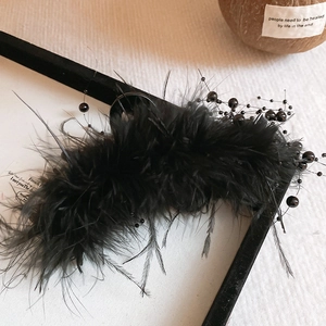 Detail shot of elegant black feather hair claw clip with beads on vintage background