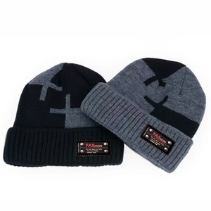 Detail of knitted winter beanie set in black and dark grey with fashion leather patches