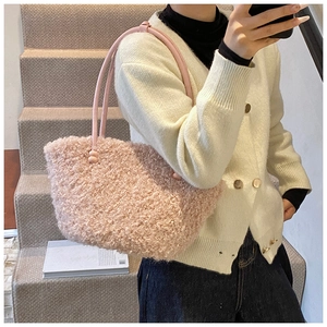 Gros plan sur un sac cabas en peluche rose avec poignées en cuir à nœuds pour femme