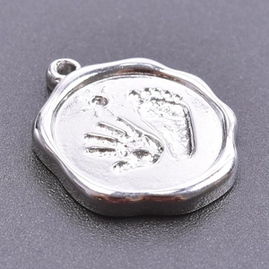 Macro shot of silver stainless steel wax seal pendant with handprint and footprint relief