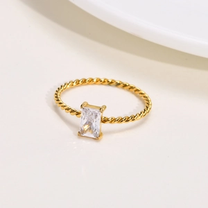 Golden stainless steel twist ring featuring a rectangular white zircon stone on white background