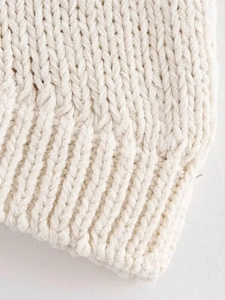 Macro shot of cream ribbed knit fabric showing soft texture and high-quality wool blend