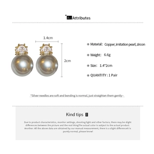 Détail de boucles d'oreilles dorées avec zircon et perle grise sur tige en argent