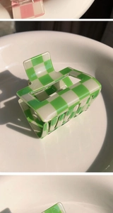 Detail shot of green and white checkerboard acrylic hair claw clip on a ceramic tray