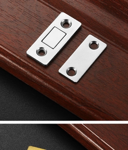 Close-up of ultra-thin silver magnetic door catch on dark wood surface hardware