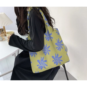 Detail of the yellow-green canvas tote bag featuring purple abstract orchid floral print