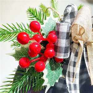 Christmas door hanger with red berries, pine needles, and black and white buffalo plaid bow