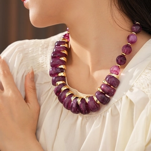 Gros plan du collier vintage avec grosses perles en résine violette et détails dorés