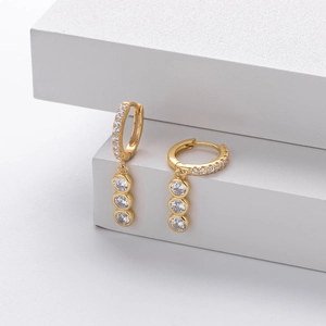 Close-up of gold plated silver earrings with pavé crystals and triple round cubic zirconia