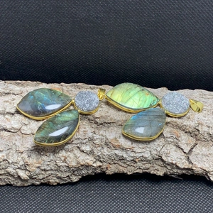 Detail view of Labradorite leaf pendants with gold plated edges on rustic wood