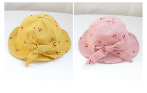 Detail view of cotton toddler sun hats in yellow and pink with cherry patterns and bows