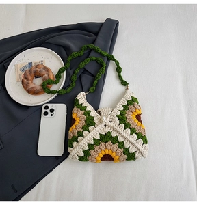 Detail of hand-crocheted sunflower granny square bag with pearl clasp and green strap