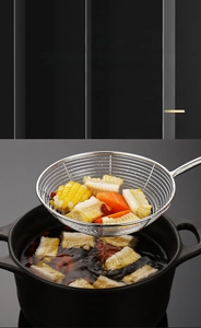 Macro shot of stainless steel mesh strainer lifting corn and carrots from a pot