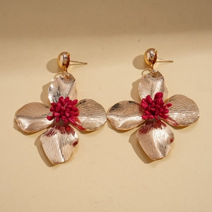 Detail of vintage gold flower earrings with red centers and textured metal petals