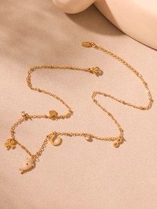 Detail shot of golden multi-element anklet with dolphin, clover and heart charms