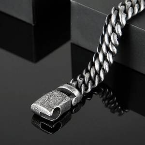 Macro detail of vintage silver Cuban link bracelet with textured mesh finish and clasp
