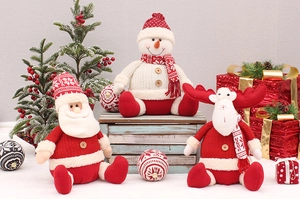 Close-up of knitted Santa, snowman and elk dolls with wooden buttons and festive textures