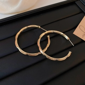 Macro view of gold hoop earrings with wave texture and C-shaped metal design