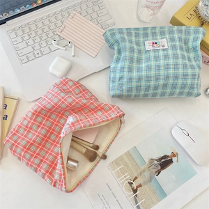 Vista flat lay di pochette per trucchi in tela a scacchi con cerniera ed etichetta logo