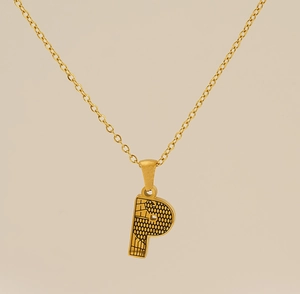 Vue macro du pendentif lettre P doré avec une texture géométrique noire moderne