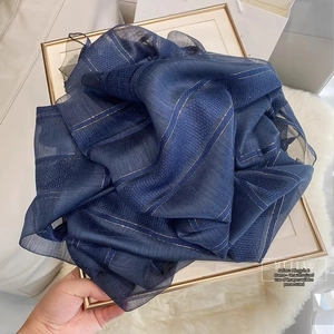 Detailed texture of dark blue silk wool scarf with metallic gold stripes on white fur
