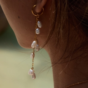 Long tassel pearl earrings in gold plated titanium steel worn by a female model