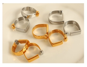 Close-up of minimalist gold and silver D-shaped rings displayed on a cream ceramic plate