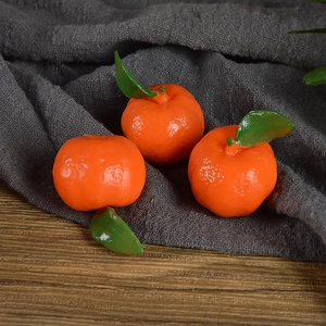 Realistic PVC miniature tangerines with green leaves on dark wooden surface backdrop