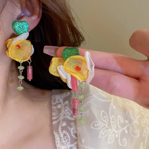 Close-up of floral fabric earrings with heart studs and colorful beaded tassel details