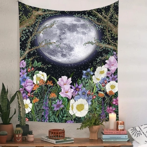 Detail of bohemian tapestry featuring a moon and floral garden design on a white wall