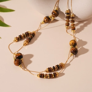 Detail of double-layer tiger eye stone necklace with golden metal spacers in warm light