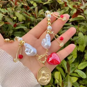 Detail of 18k gold heart cherry pendant necklace with baroque pearls and religious medal