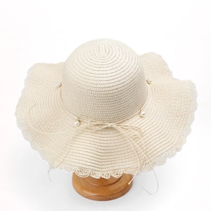 Close-up of wavy brim sun hat featuring pearl trim decoration and delicate bow detail