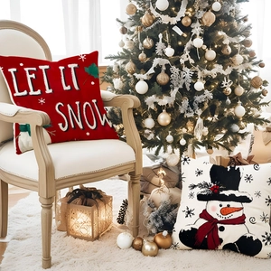 Christmas pillow covers with snowman and Let It Snow text on a white armchair