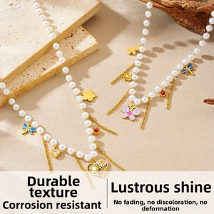 Dettaglio della collana di perle con ciondoli a farfalla smaltata, cuori e nappe