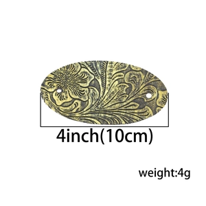 Detail view of oval antique bronze hair charm with floral engraving and 4 inch size specs